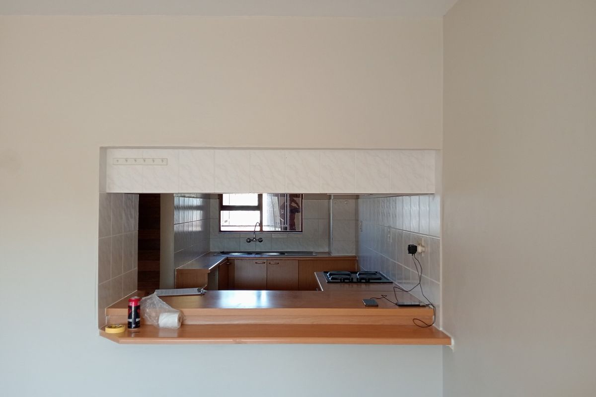 A functional kitchen featuring a breakfast bar pass-through, built-in cabinetry, gas hob, and stainless steel sink, offering a practical layout for daily use.