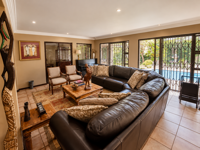 Spacious living room featuring tiled flooring, recessed lighting, and large sliding glass doors that provide direct access to the outdoor pool area.
