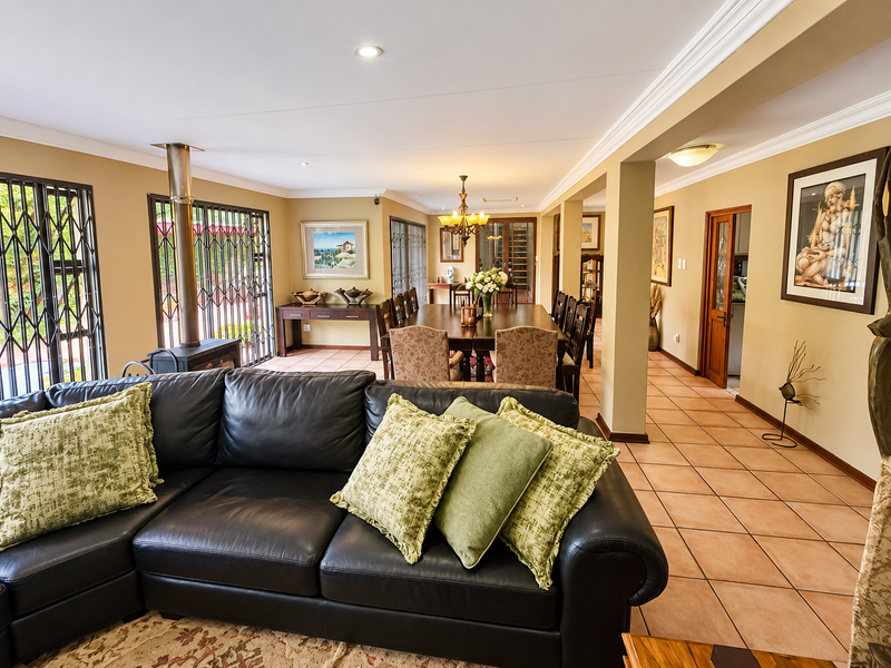 Spacious open-plan living and dining area featuring ceramic tile flooring, a freestanding fireplace, and elegant crown molding throughout the connected living spaces.