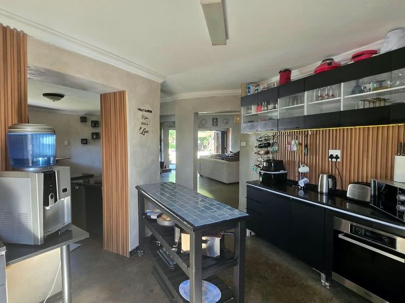 Modern kitchen featuring sleek black cabinetry, integrated oven, and stylish slatted wood wall paneling, creating a contemporary and functional culinary space.