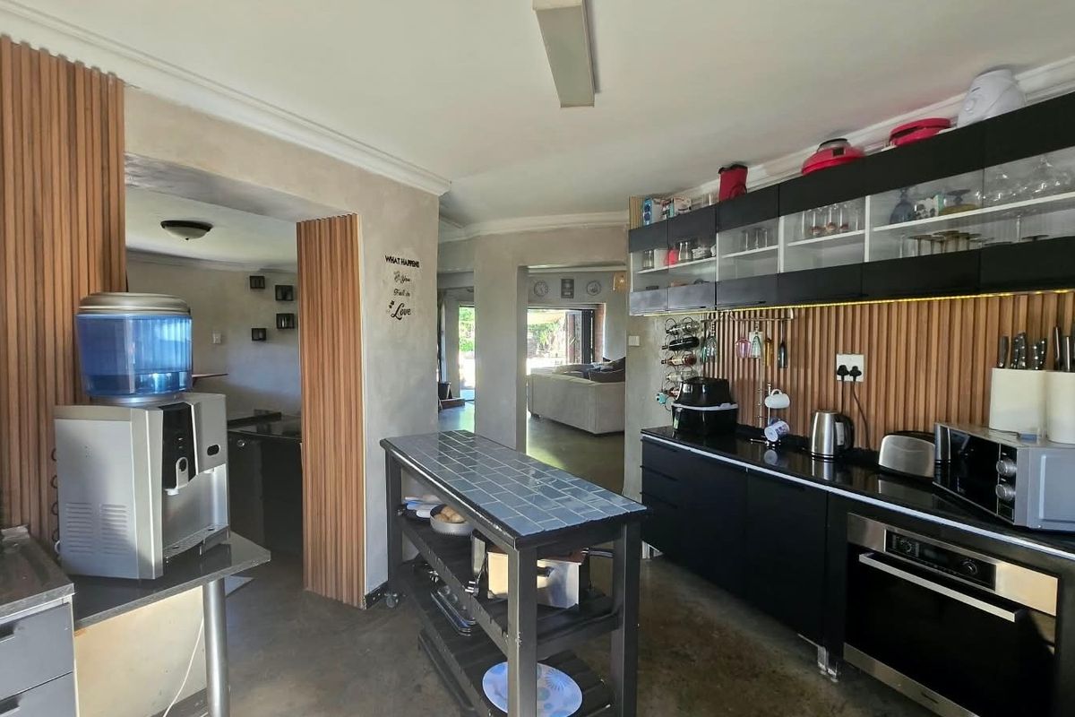 Modern kitchen featuring sleek black cabinetry, integrated oven, and stylish slatted wood wall paneling, creating a contemporary and functional culinary space.