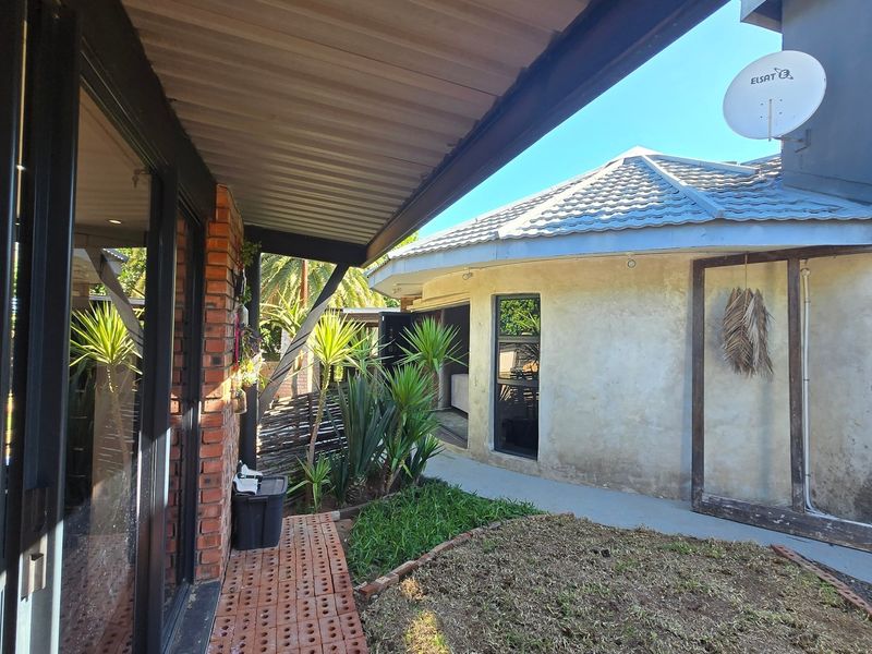 A covered patio area featuring brick paving and access to the main dwelling through sliding glass doors, overlooking a small garden space.