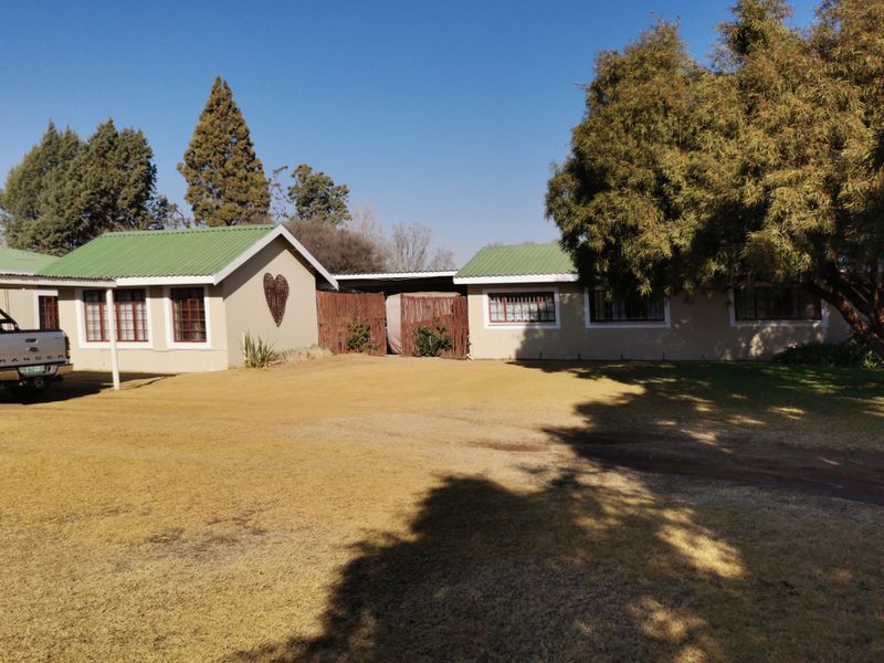 Front exterior view of the industrial property featuring a green corrugated metal roof, timber-framed windows, and a spacious lawn area.