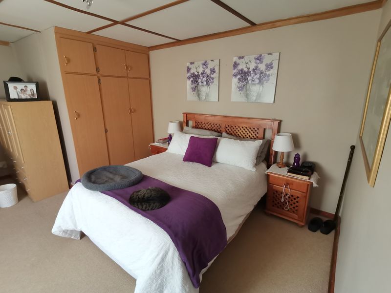 A bedroom featuring built-in wooden cupboards and a suspended ceiling grid, offering a functional space with potential for modern updates.