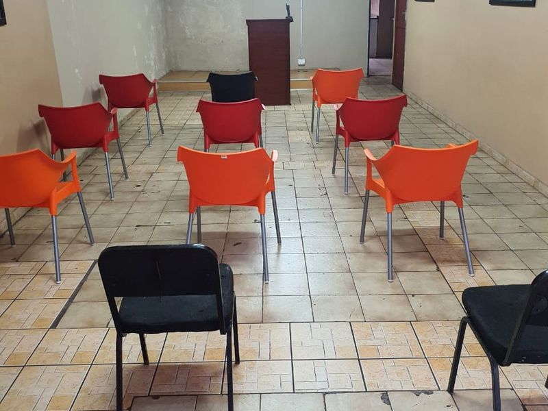 A functional commercial meeting or training room featuring tiled flooring, a raised platform, and wall-mounted air conditioning, currently set up with seating.