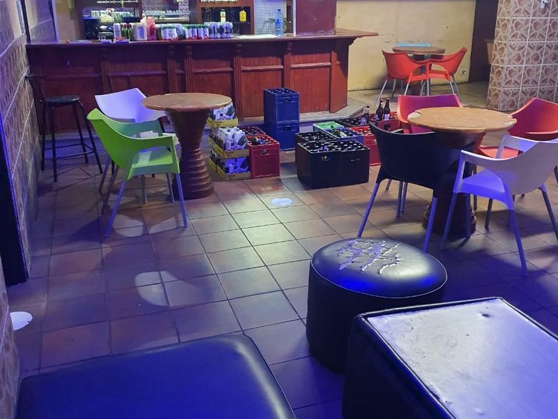 A commercial bar area featuring a built-in service counter, tiled flooring, and tiled wall accents, currently set up with casual seating.