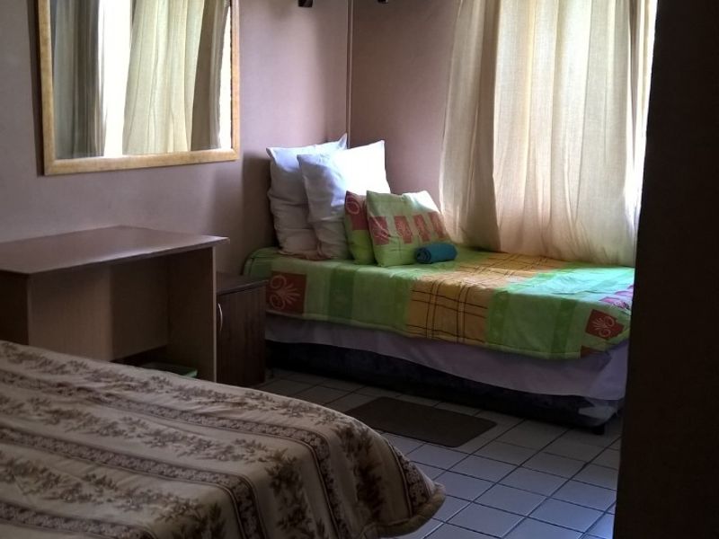 A compact bedroom featuring tiled flooring, a wall-mounted air conditioning unit, and a wall-mounted television bracket, offering a functional layout for accommodation.