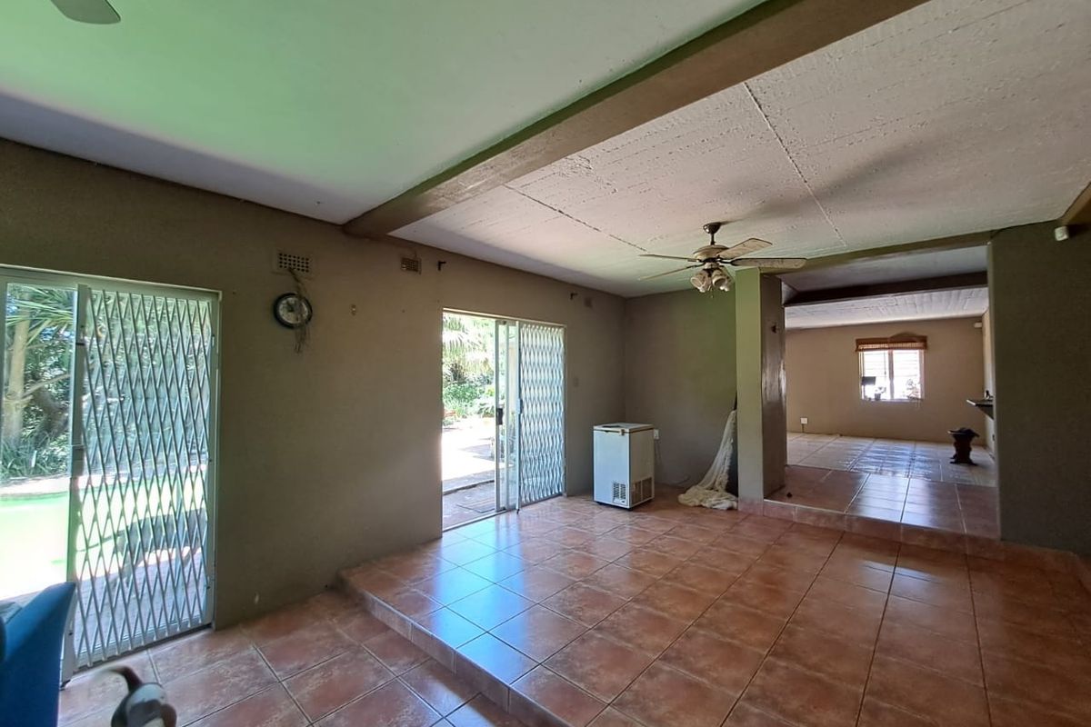 Spacious open-plan living area featuring ceramic tile flooring, a raised floor section, and sliding security doors leading to the garden.