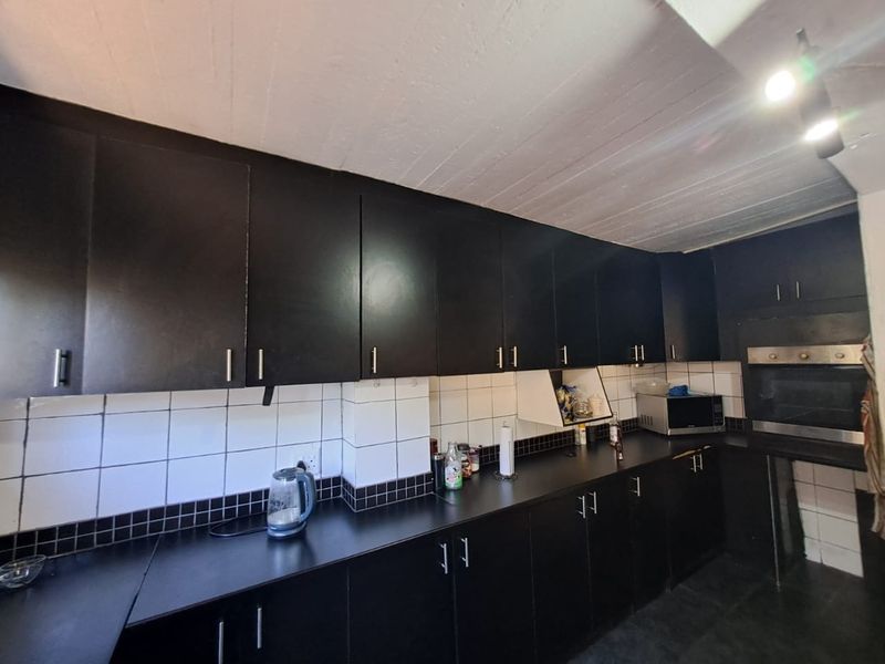 A functional kitchen featuring dark built-in cabinetry, tiled backsplash, and a built-in oven, offering a solid foundation for a modern renovation.