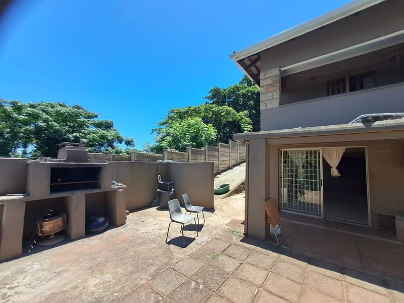 Outdoor patio area featuring a built-in braai, paved flooring, and direct access to the interior through a sliding glass door.