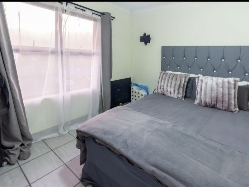 A bedroom featuring tiled flooring and a wall-mounted television bracket, providing a functional space with natural light from the window.