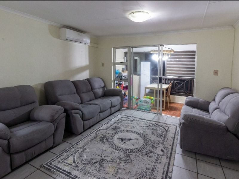 A living room featuring tiled flooring, an air conditioning unit, and a sliding glass door providing access to an outdoor balcony area.