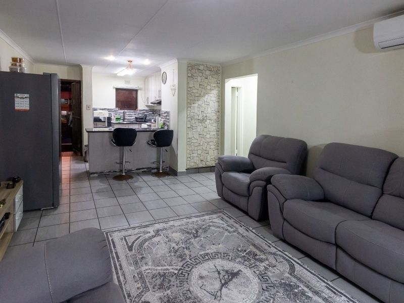 Open-plan living area featuring tiled flooring, a kitchen with a breakfast bar, and a split-system air conditioner.