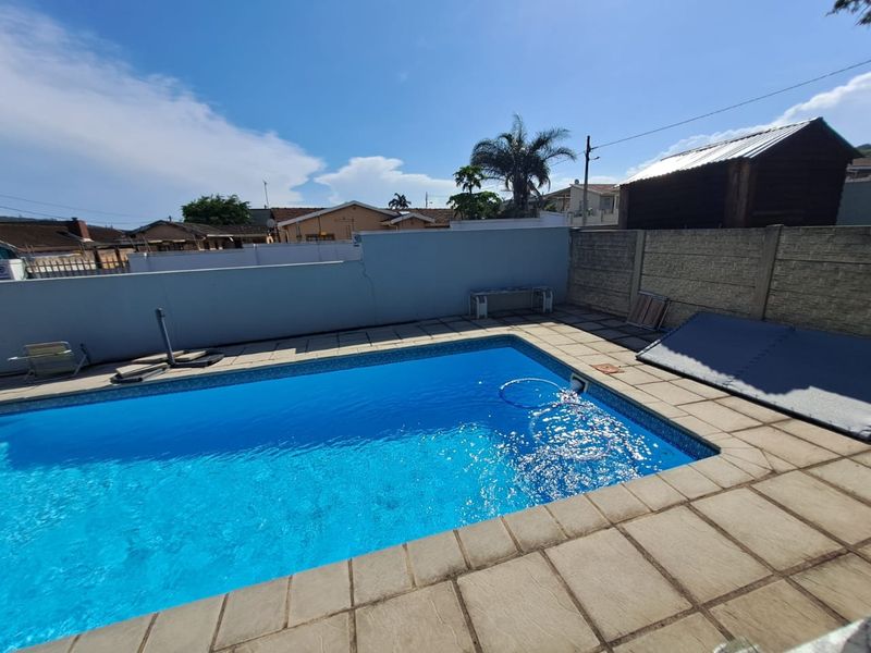 Outdoor pool area featuring a swimming pool with a paved deck and surrounding boundary walls.