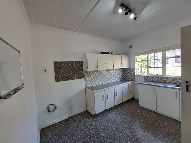 A functional kitchen space featuring white built-in cabinetry, tiled backsplash, and tiled flooring, offering a blank canvas for potential modern updates.