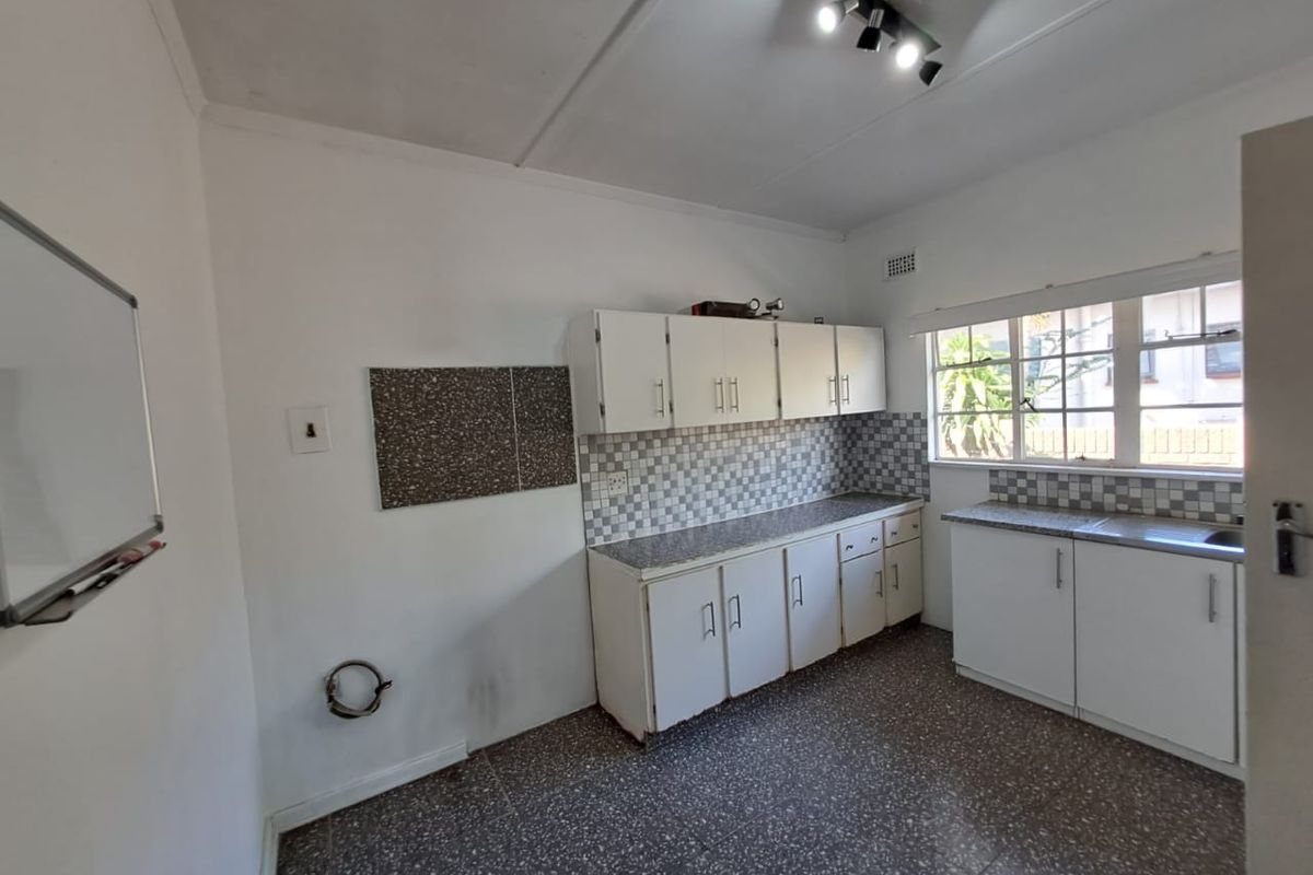 A functional kitchen space featuring white built-in cabinetry, tiled backsplash, and tiled flooring, offering a blank canvas for potential modern updates.