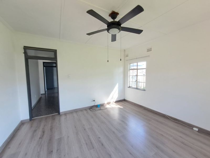 An empty bedroom featuring light-toned laminate flooring, a ceiling fan, and neutral walls, offering a blank canvas for personalization.
