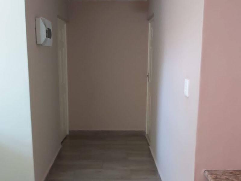 A simple, empty hallway featuring laminate flooring, neutral wall tones, and access to adjacent rooms via internal doors.
