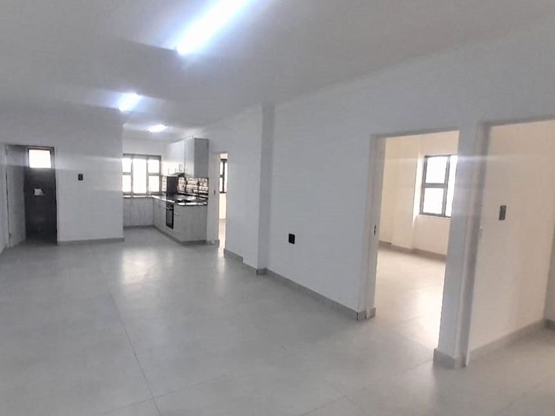 Spacious open-plan living area featuring tiled floors and a functional kitchen with built-in cabinetry and appliances.