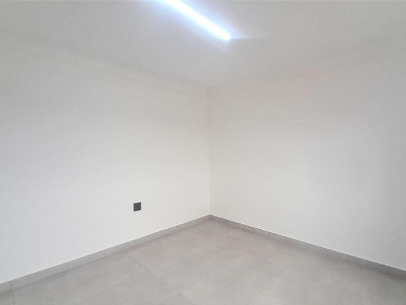 A clean, empty bedroom featuring neutral tiled flooring and a simple ceiling light fixture, ready for personalization.