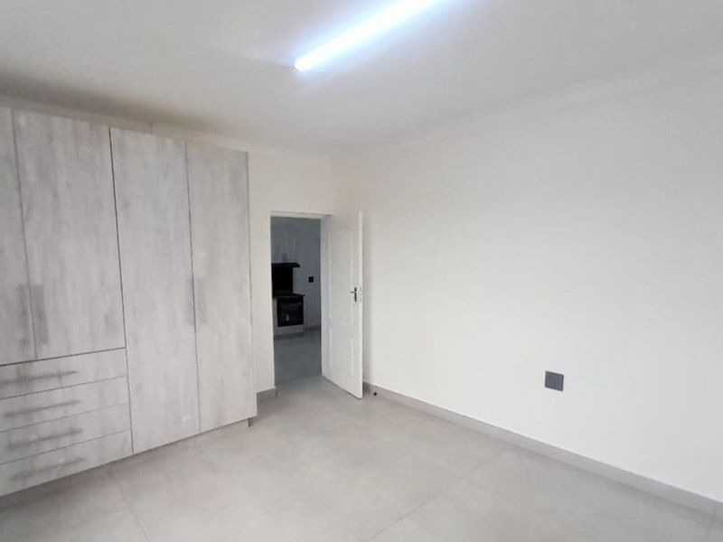 A clean, empty bedroom featuring neutral tiled flooring and modern built-in cupboards, offering a blank canvas for personalization.