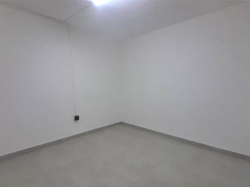 A vacant, neutral-toned bedroom featuring tiled flooring and basic electrical fixtures, offering a blank canvas for personalization.