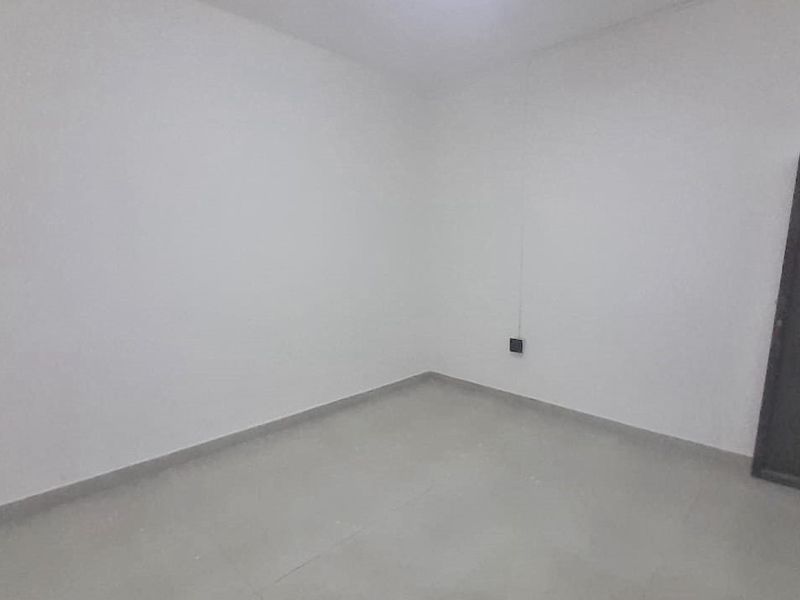 A simple, empty bedroom featuring neutral tiled flooring and white walls, providing a blank canvas for personalization.