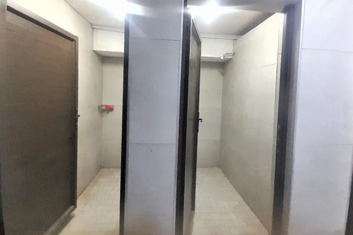 A functional bathroom area featuring tiled walls and flooring with separate shower cubicles.