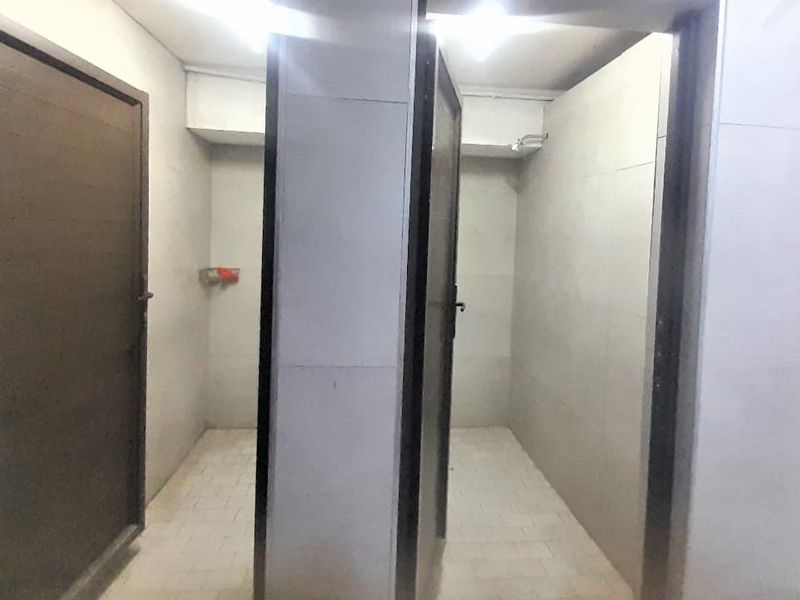 A functional bathroom area featuring tiled walls and flooring with separate shower cubicles.