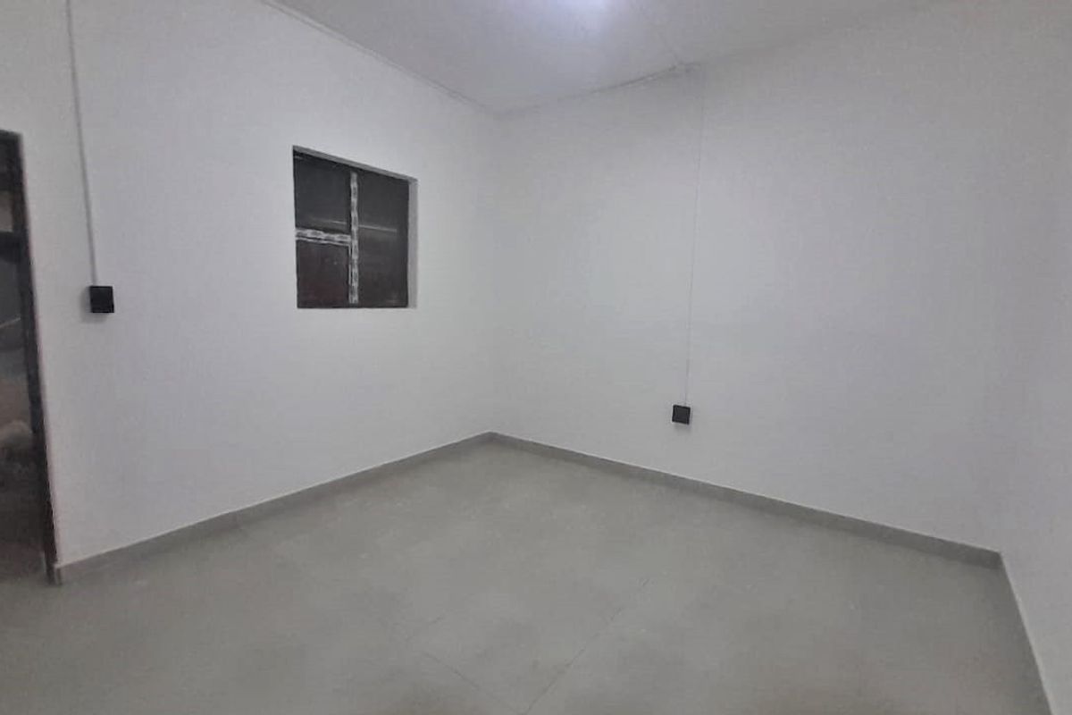 A clean, empty bedroom featuring neutral tiled flooring and white walls, providing a blank canvas for personalization.