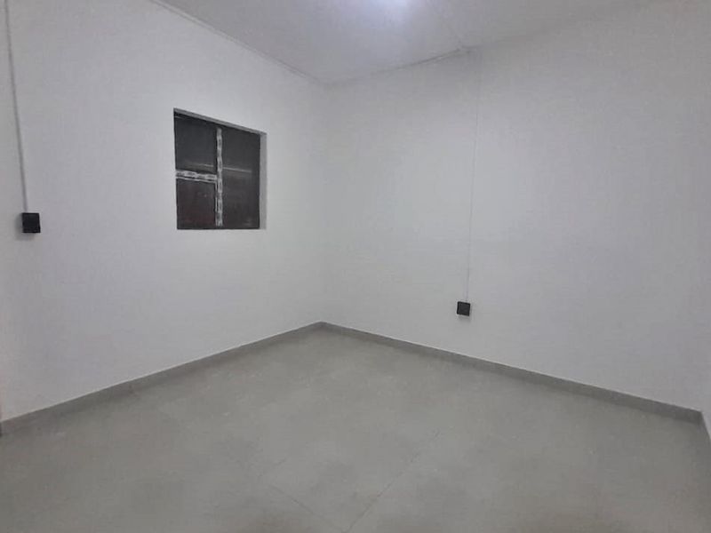 A clean, empty bedroom featuring neutral tiled flooring and white walls, providing a blank canvas for personalization.