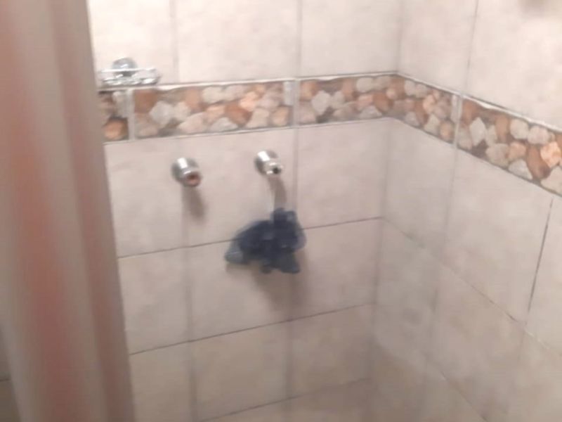 A small shower enclosure featuring tiled walls with a decorative border, currently missing a shower head fixture.