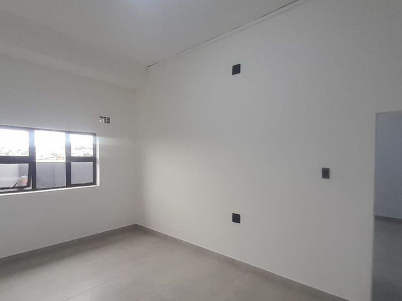 A clean, empty bedroom featuring neutral tiled flooring, white walls, and an aluminium-framed window, providing a blank canvas for personalization.