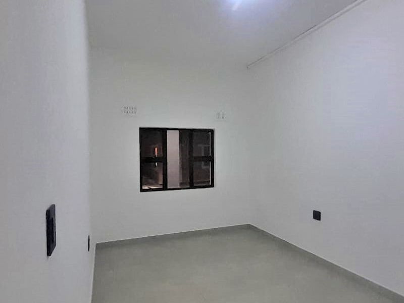 A clean, empty bedroom featuring neutral tiled flooring, white walls, and a dark-framed window, providing a blank canvas for personalization.