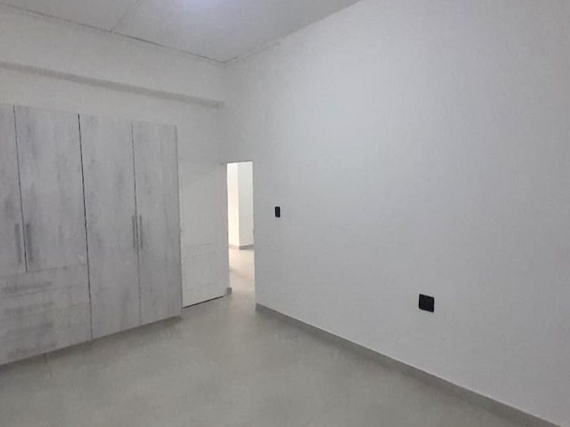 A clean, empty bedroom featuring neutral tiled flooring and modern built-in cupboards, offering a blank canvas for personalization.