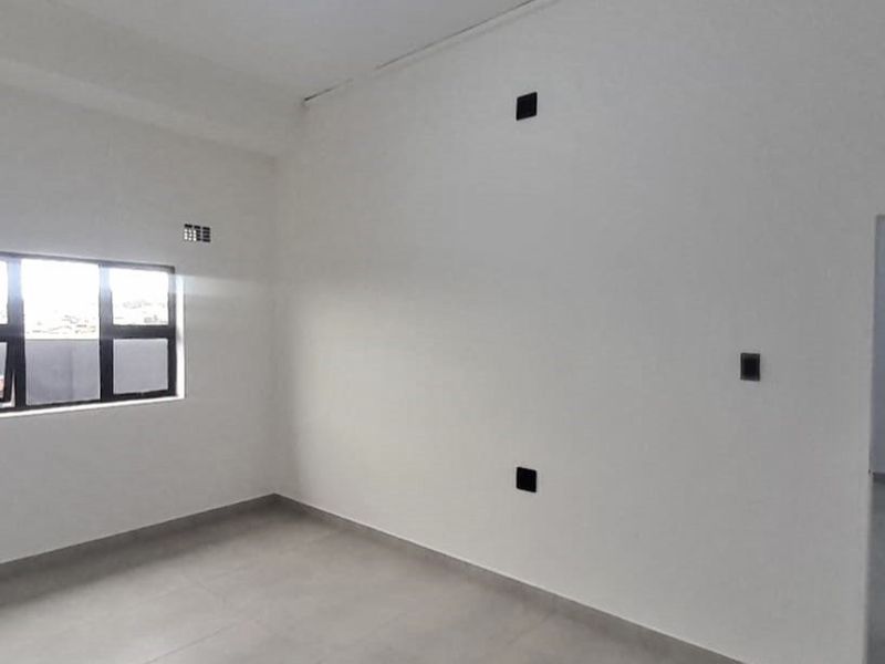 A bright, empty living area featuring neutral tiled flooring and clean white walls, ready for personalization.