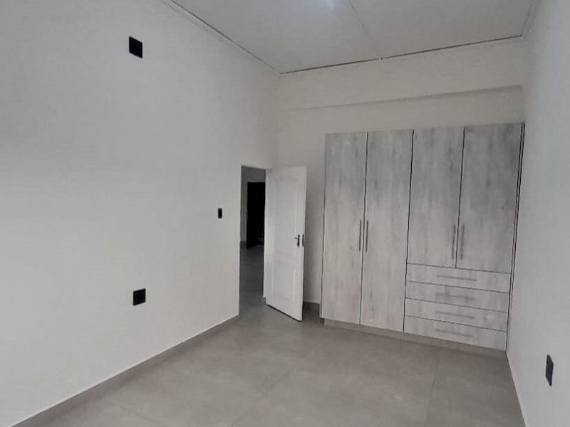 A clean, empty bedroom featuring neutral tiled flooring and modern built-in cupboards with ample storage space.