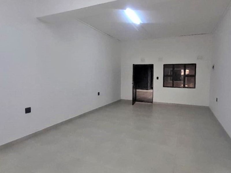 An empty, open-plan living area featuring neutral tiled flooring and basic lighting, providing a blank canvas for interior design and personalization.