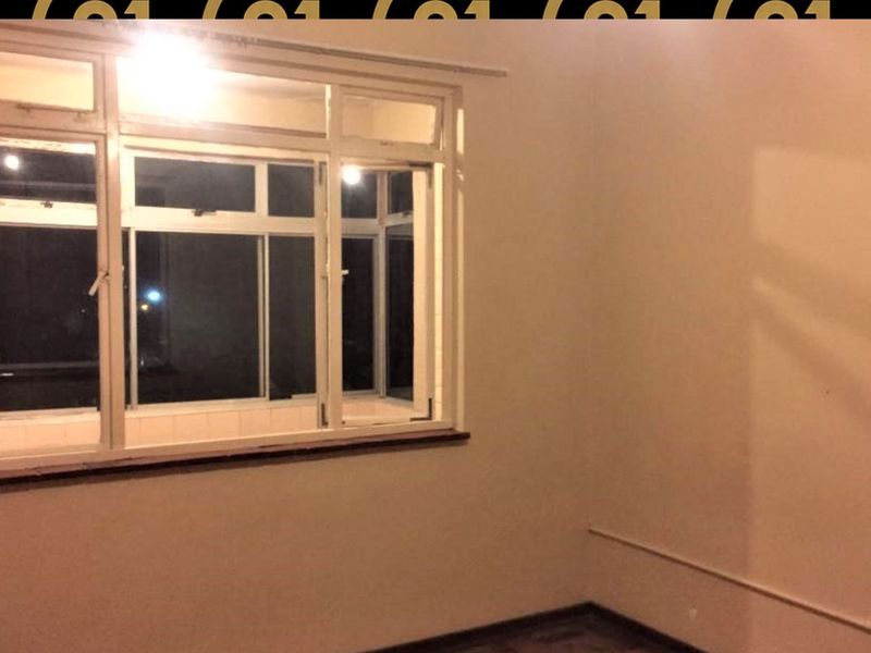 An empty bedroom featuring a large multi-pane window with a sill, providing natural light and a view of the exterior.