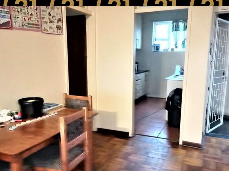 Open plan living area featuring parquet flooring, leading into a functional kitchen space with tiled floors and a secure entrance door.