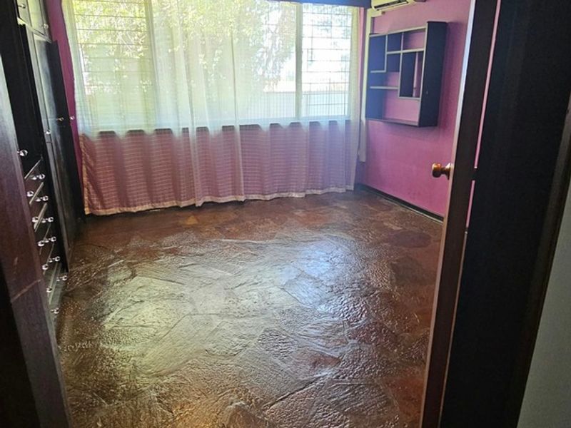 An empty bedroom featuring unique stone flooring, built-in storage, and a wall-mounted air conditioning unit.