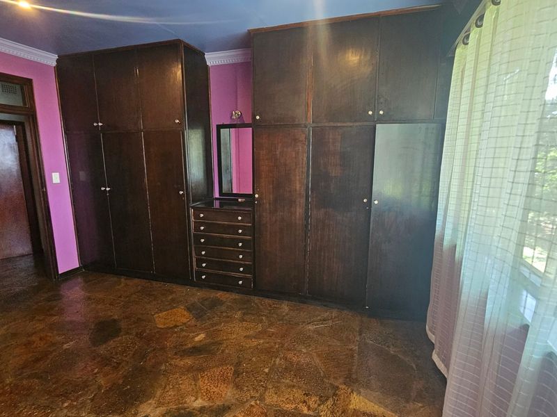 Spacious bedroom featuring extensive dark wood built-in cabinetry with integrated vanity and unique stone flooring.