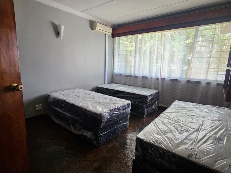 A bedroom featuring an air conditioning unit, built-in shelving, and a large window with natural light.