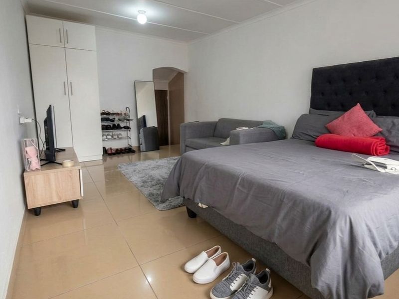 A bedroom featuring tiled flooring and a built-in wardrobe, offering a functional living space.