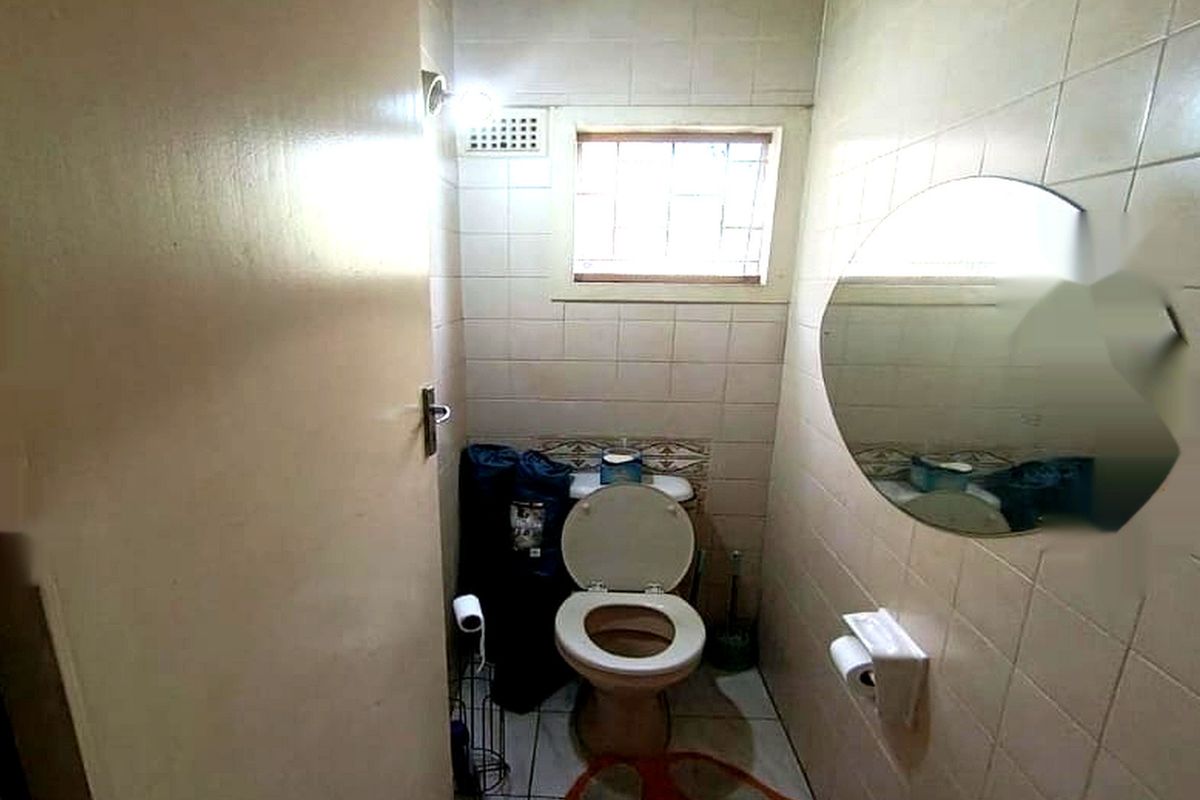 A compact bathroom featuring tiled walls and flooring, a standard toilet, and a small window for natural light and ventilation.