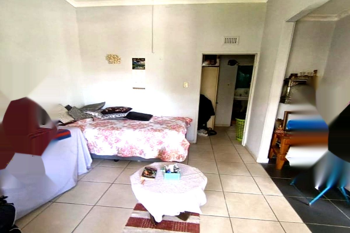 A bedroom featuring tiled flooring and a neutral wall finish, providing a functional space with direct access to an adjoining room.