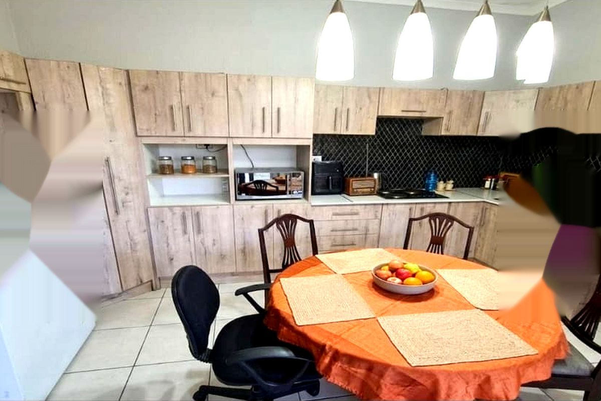 A functional kitchen featuring light wood-tone cabinetry, a dark tiled backsplash, and tiled flooring, providing a practical layout for daily meal preparation.