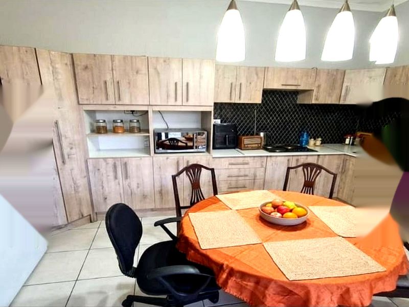 A functional kitchen featuring light wood-tone cabinetry, a dark tiled backsplash, and tiled flooring, providing a practical layout for daily meal preparation.