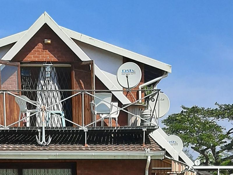 An elevated balcony featuring a metal balustrade and brick exterior wall, providing outdoor space with multiple satellite dish installations.