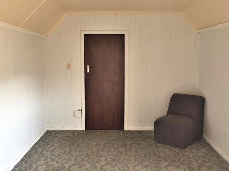 A bedroom featuring sloped ceilings and wall paneling, offering a blank canvas for renovation and modernization.